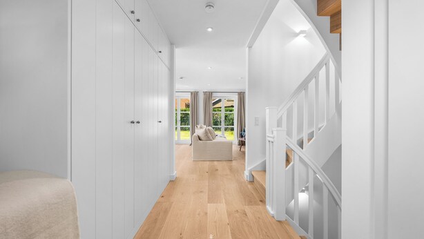 A hallway with wooden flooring, white walls, and a staircase with white railings. - Spacious 5-Star Villa with Sauna, Garden and Private Terrace in Tinnum (Tinnum)