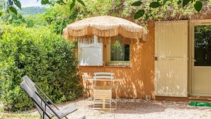 A small, rustic building with a thatched roof, a wooden bench, and a door.