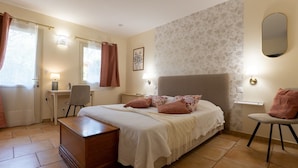 A bedroom with a bed, bedside tables, a desk, a chair, and a dresser.