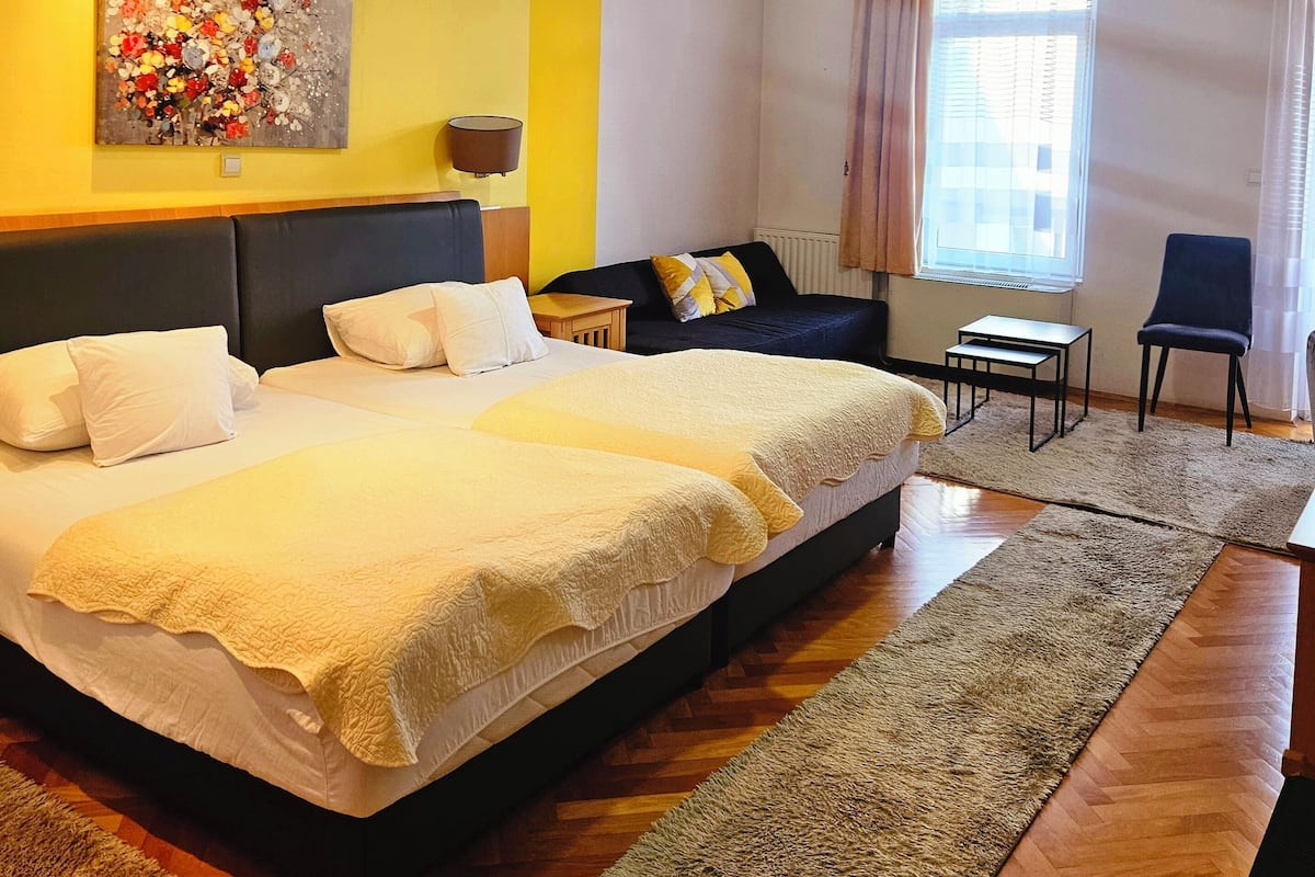 A bedroom with a large bed, a sofa, a small table, and a chair.