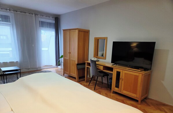A hotel room with a bed, a desk with a chair, a television, and a wardrobe. - HOTEL MILLENNIUM (Osijek)