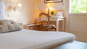 Ein Schlafzimmer mit einem Bett, einem Schreibtisch, einem Stuhl, einer Lampe, einem Fenster und einem Bild an der Wand.