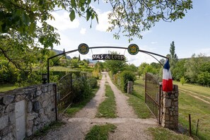 A stone pathway leading to a gate with a sign reading 'MAS du Loup.'