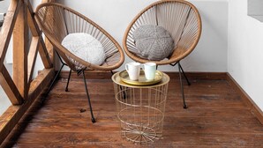 A corner room with two wicker chairs, a small round table with a tray, and decorative wall hangings. - Apartamenty Stare Bielsko (Bielsko-Biała)