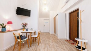 A modern interior with a dining area, a TV mounted on the wall, and a wooden floor. - Apartamenty Stare Bielsko (Bielsko-Biała)