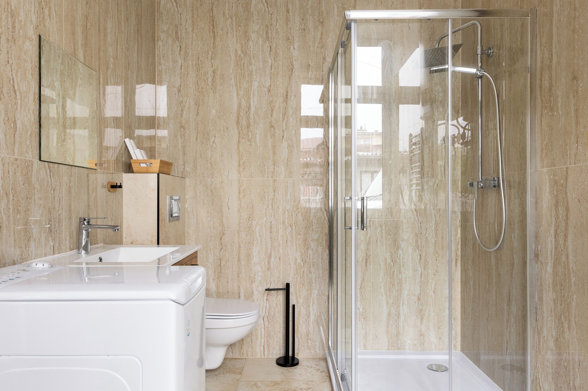 Une salle de bain moderne avec une douche à parois de verre, un lavabo blanc et des toilettes.
