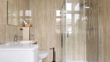 Une salle de bain moderne avec une douche à parois de verre, un lavabo blanc et des toilettes.