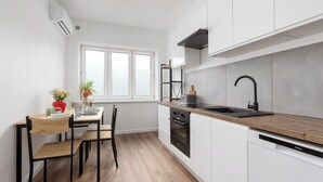 A modern kitchen with white cabinets, a wooden countertop, a black sink, and a built-in oven. - Apartamenty Stare Bielsko (Bielsko-Biała)