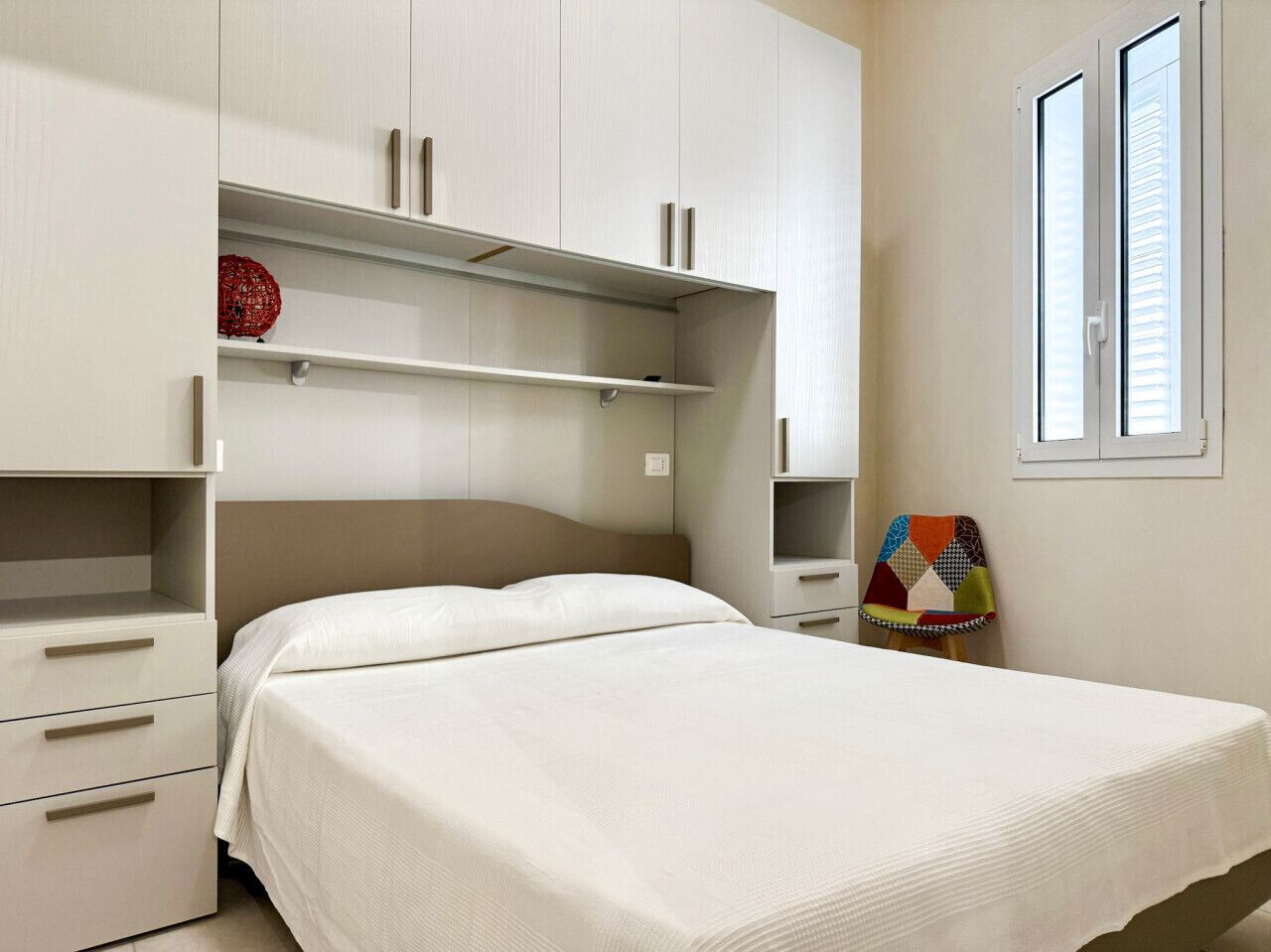 Ein Schlafzimmer mit einem Bett, einem Kleiderschrank und einem Fenster.