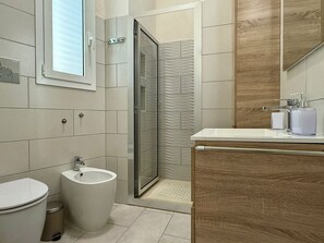Ein modernes Badezimmer mit Toilette, Bidet und Dusche mit Glastür.