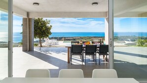 A modern dining area with a table and chairs, overlooking a scenic ocean view. - Villa Lily with private pool - My Rental Homes (Montallegro)