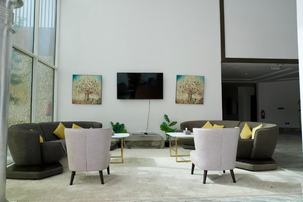 A spacious lobby with two sofas, a flat-screen TV, and two paintings on the wall.