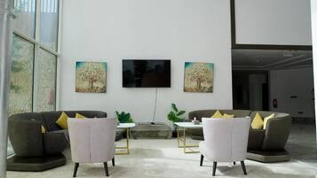 A spacious lobby with two sofas, a flat-screen TV, and two paintings on the wall.