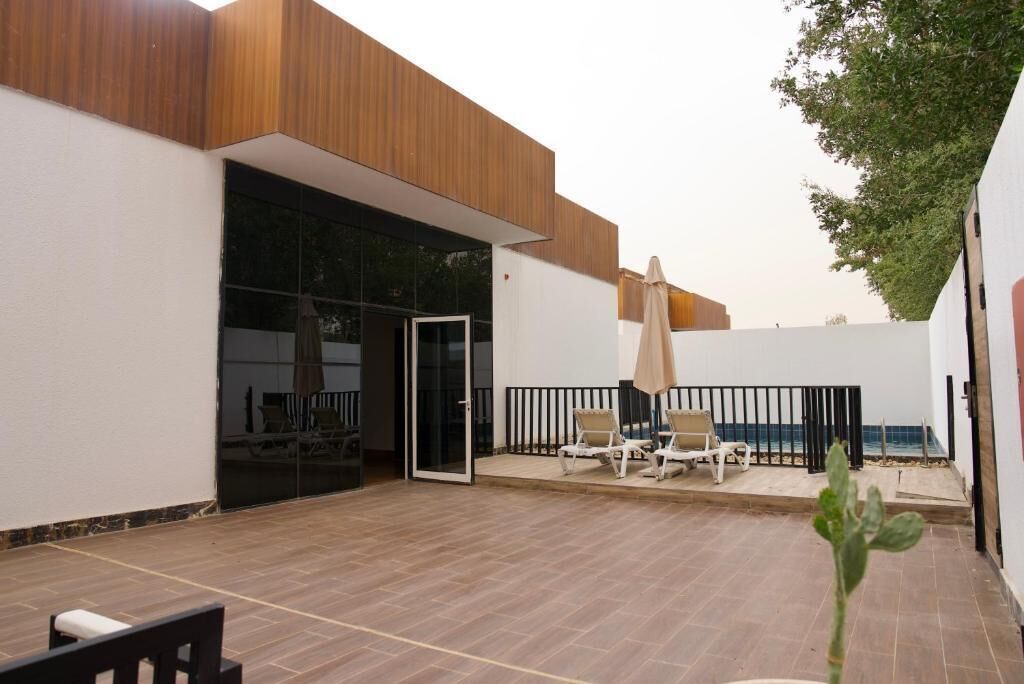 A modern outdoor patio with a sliding glass door, lounge chairs, and a small table.
