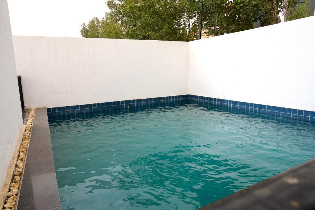 A swimming pool with blue tiles, surrounded by white walls.