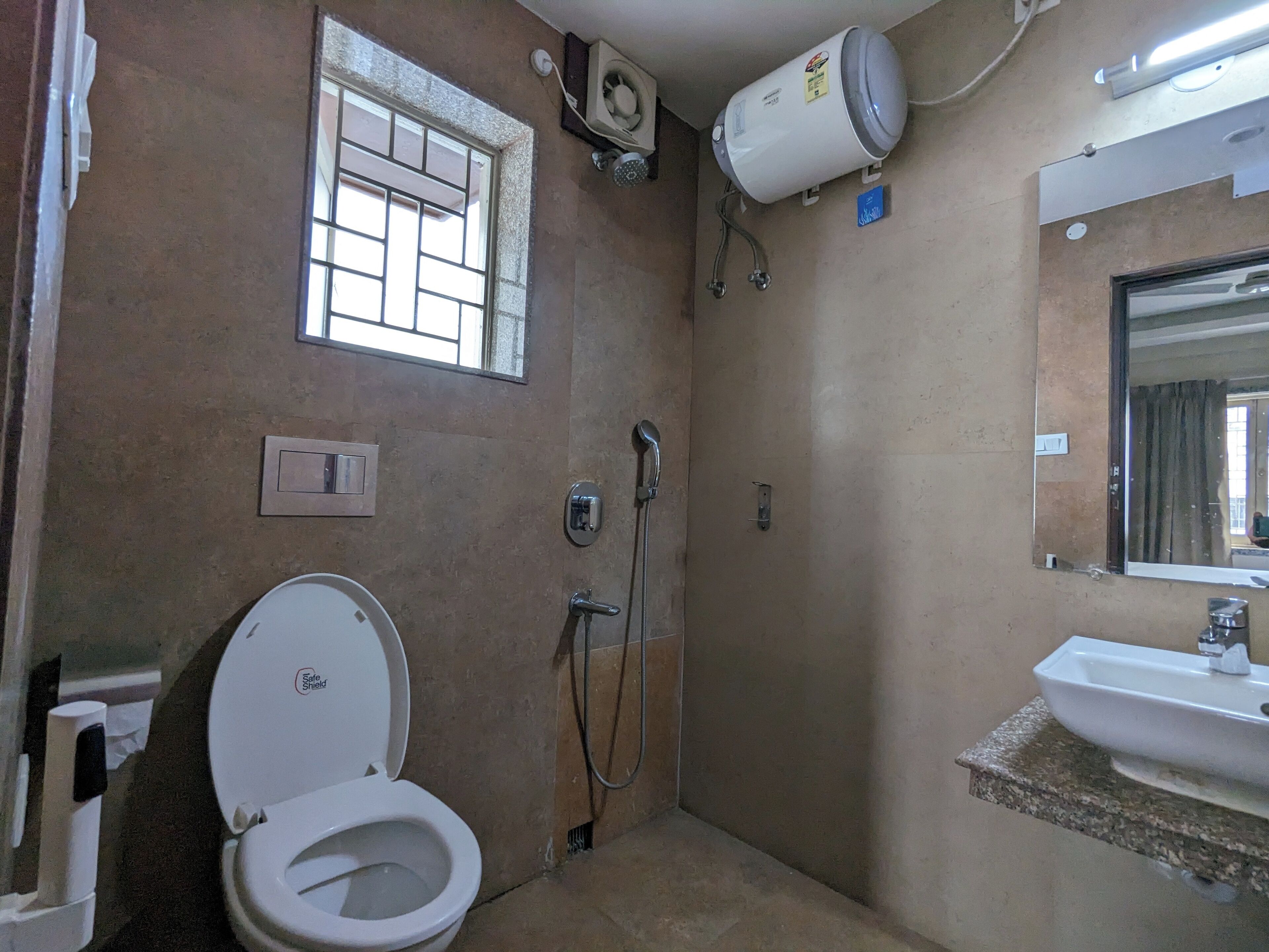 Een kleine badkamer met toilet, douche en wastafel.