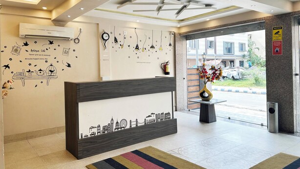 A reception area with a modern design, including a reception desk, decorative wall art, and a view of the outside. - The Aster Enclave (Barasat)