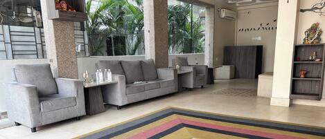 A modern living room with grey sofas, a patterned rug, and a decorative shelf with items.