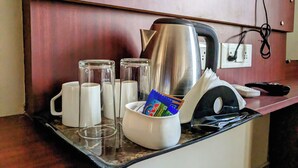 A kitchen counter with a kettle, two glasses, a mug, and a container with cards. - The Aster Enclave (Barasat)