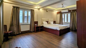 A spacious bedroom with a large bed, a ceiling fan, and a wooden floor. - The Aster Enclave (Barasat)