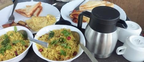 A breakfast setting with plates of food, a coffee pot, and utensils.