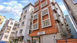 A multi-story hotel with a modern facade, featuring balconies with intricate lattice designs. - The Aster Enclave (Barasat)