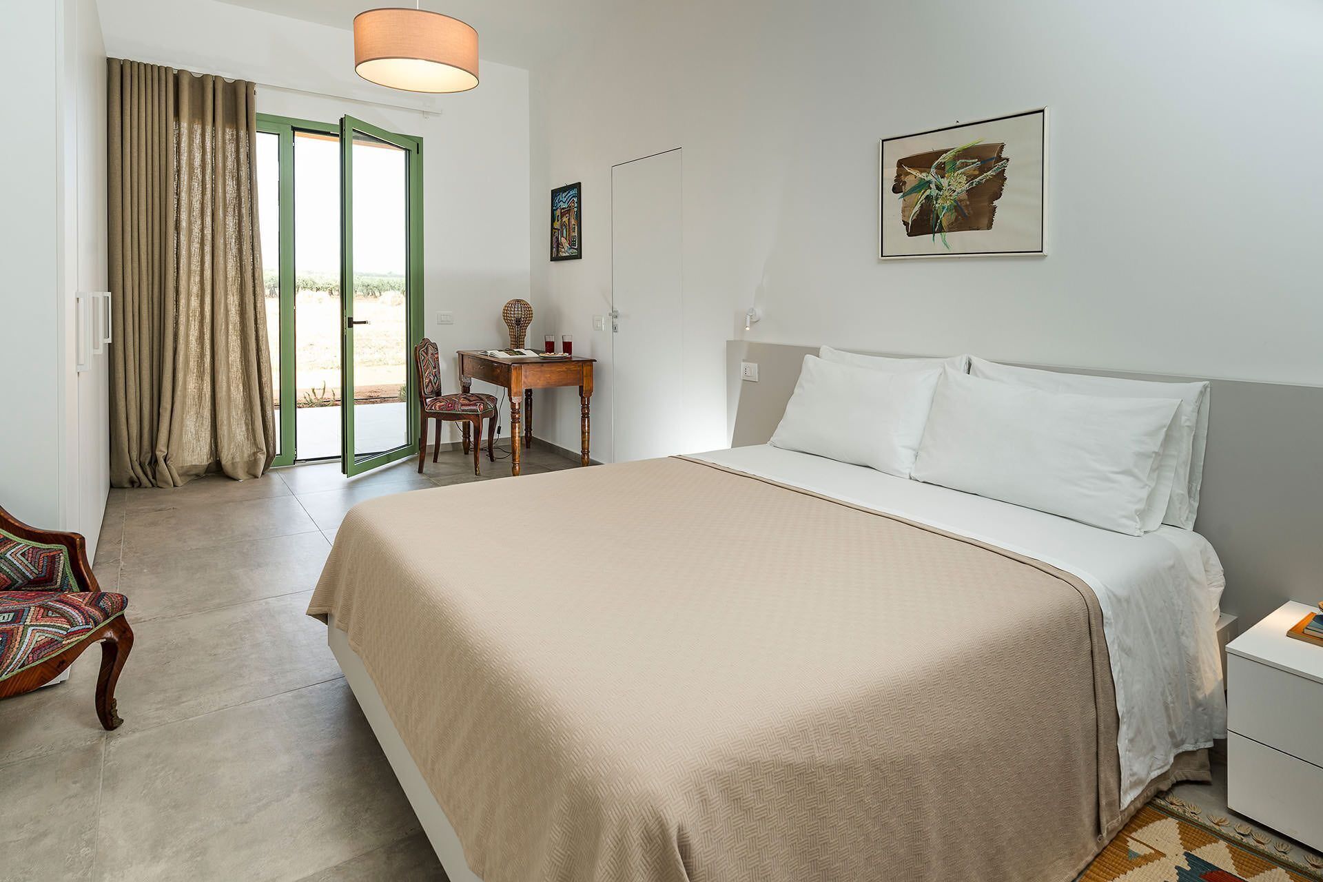 Une chambre d’hôtel avec un grand lit, un bureau, une chaise et un tableau au mur.