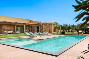 A poolside area with lounge chairs and a stone building.