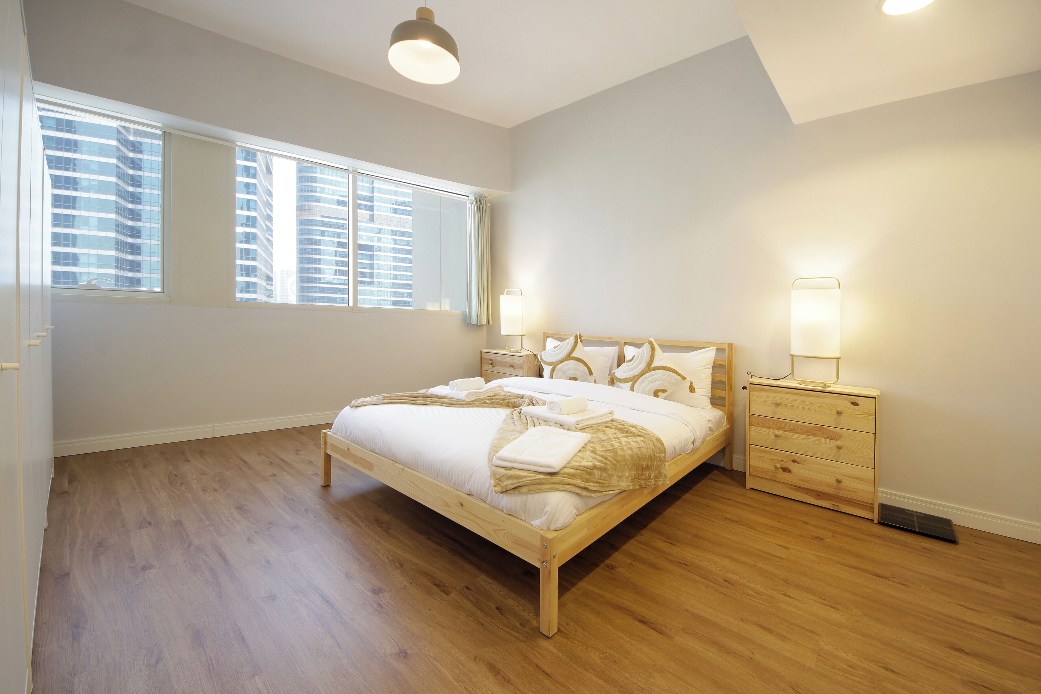 Une chambre à coucher avec un lit en bois, des tables de chevet et une fenêtre avec des stores.