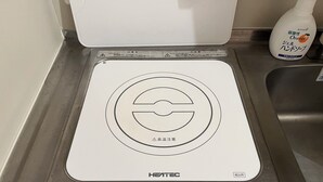 Um fogão elétrico HEATEC com painel de controle digital, uma pia e um frasco de sabonete laranja.