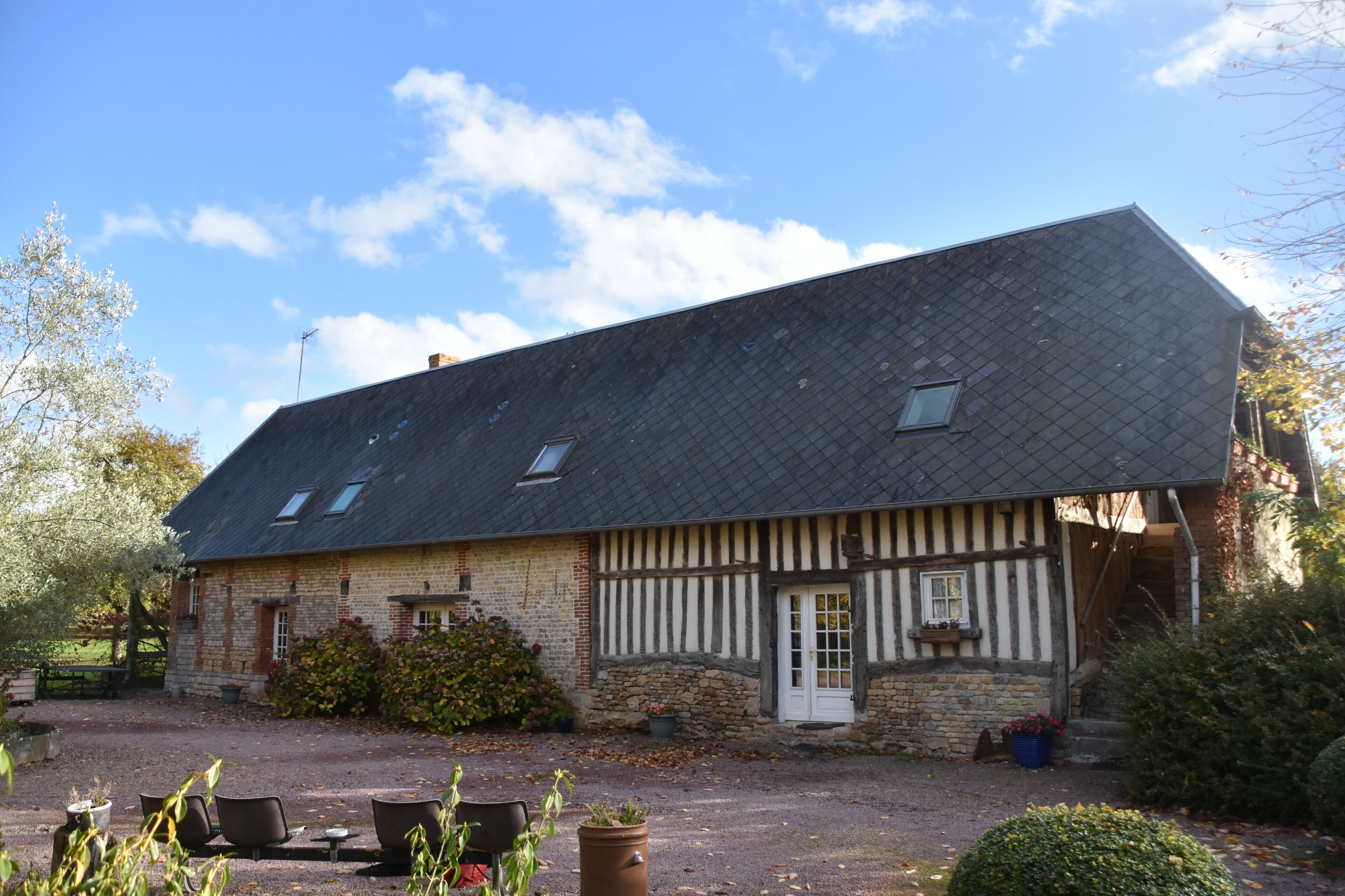A traditional half-timbered house with a gravel driveway and outdoor seating area.