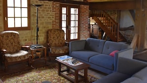 Uma sala de estar rústica com sofá, poltronas, mesa de centro e escada.