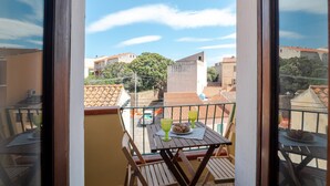 Ein Balkon mit Tisch, zwei Stühlen und einem Teller Essen.