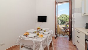 Ein Essbereich mit Tisch für zwei Personen, einem an der Wand montierten Fernseher und einer Küchenzeile mit Kühlschrank.
