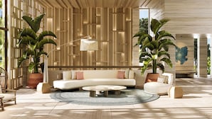 Un salon moderne avec un canapé d’angle, une table basse et de grandes plantes en pot.