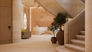Un intérieur moderne avec un comptoir d’accueil, un escalier et une grande plante en pot.