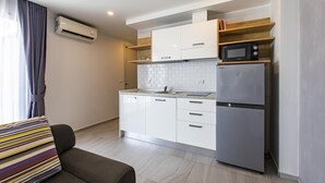 Una cocina moderna con armarios blancos, microondas integrado y refrigerador de acero inoxidable.