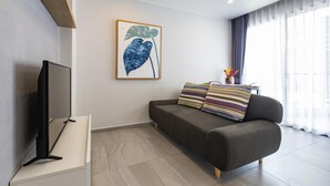 Una sala de estar moderna con un sofá gris, cojines a rayas, un televisor de pantalla plana y una obra de arte enmarcada en la pared.