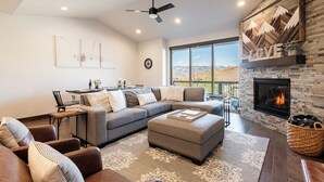 A modern living room with a sectional sofa, ottoman, and a fireplace. - Family-Friendly Escape w/ Hot Tub & Views | Near Jordanelle & Ski Resorts (Hideout)
