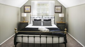 A bedroom with a bed, two bedside tables, a window with curtains, and framed pictures on the wall. - Cartref - Cartref - Home away from Home (Mount Dandenong)