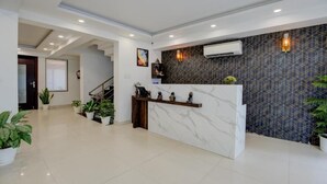 A reception area with a marble counter, potted plants, and a geometric patterned wall.