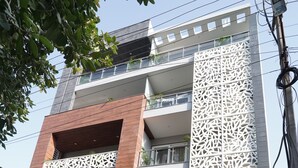 A modern building with a unique facade, featuring a mix of wooden and white panels, and balconies with plants.