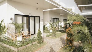Un hôtel moderne doté d’un espace extérieur abrité, agrémenté de chemins en pierre, de plantes en pot et de mobilier en bois.