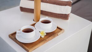 Un plateau avec deux tasses de café et un dessert à plusieurs couches, posé sur une table blanche.
