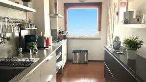 A compact kitchen with white cabinets, a window, and a tiled floor. - Casa Thibaut (Poggi)