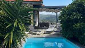 A swimming pool with lounge chairs and a patio area, surrounded by greenery and a view of distant mountains. - Casa Thibaut (Poggi)
