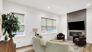 A modern living room with a sofa, armchairs, a fireplace, and a large window. - Modern Luxury | Fireplace | Rooftop Deck | Near DT (Indianapolis)
