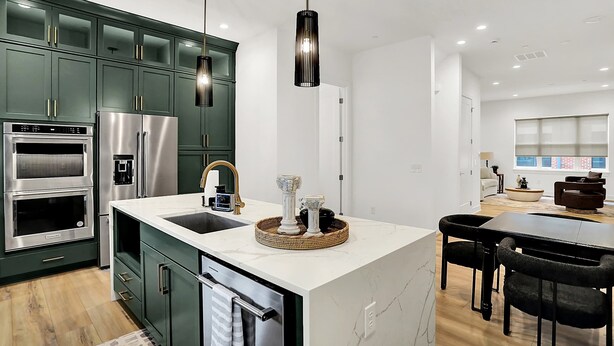 A modern kitchen with dark green cabinets, stainless steel appliances, a marble island, and pendant lighting. - Modern Luxury | Fireplace | Rooftop Deck | Near DT (Indianapolis)
