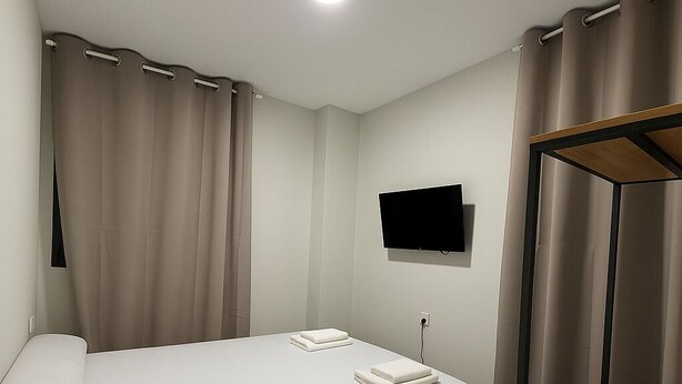 A hotel room with a single bed, a flat-screen TV mounted on the wall, and a wooden wardrobe. - Hostal Alcorcon (Alcorcón)