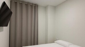 A modern hotel room with a large bed, a flat-screen TV mounted on the wall, and a window with curtains. - Hostal Alcorcon (Alcorcón)
